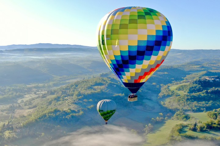 Two colorful hot air balloons floating above a scenic landscape.